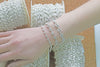 Silver mariner chain bracelet on a wrist with spools of chain in the background