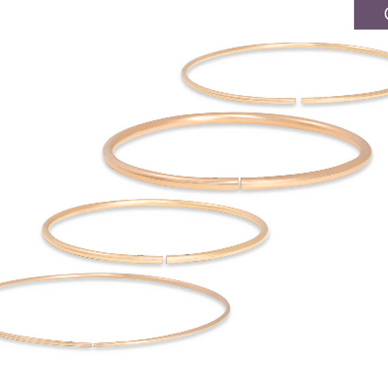 Set of gold permanent bangles on a white background