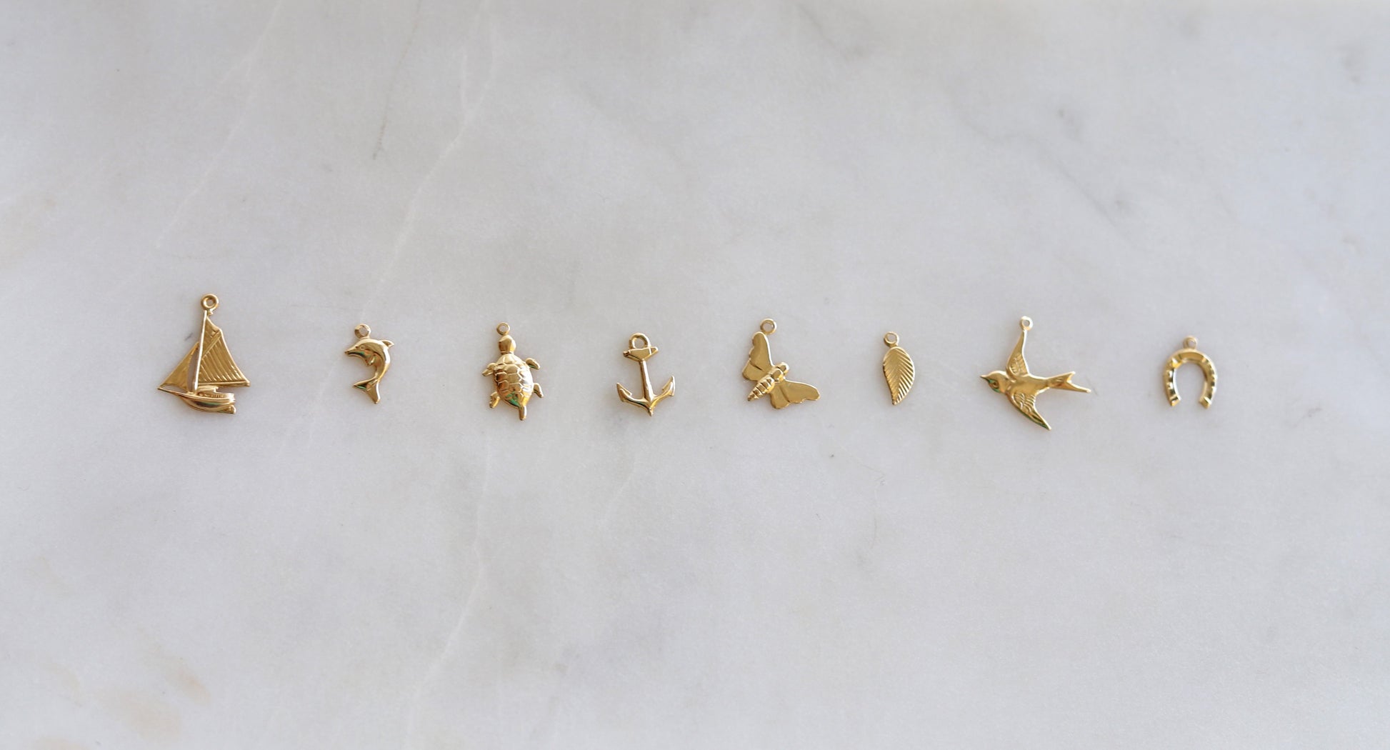 Set of gold charm pendants on a light gray background