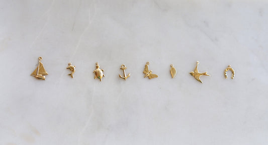 Set of gold charm pendants on a light gray background