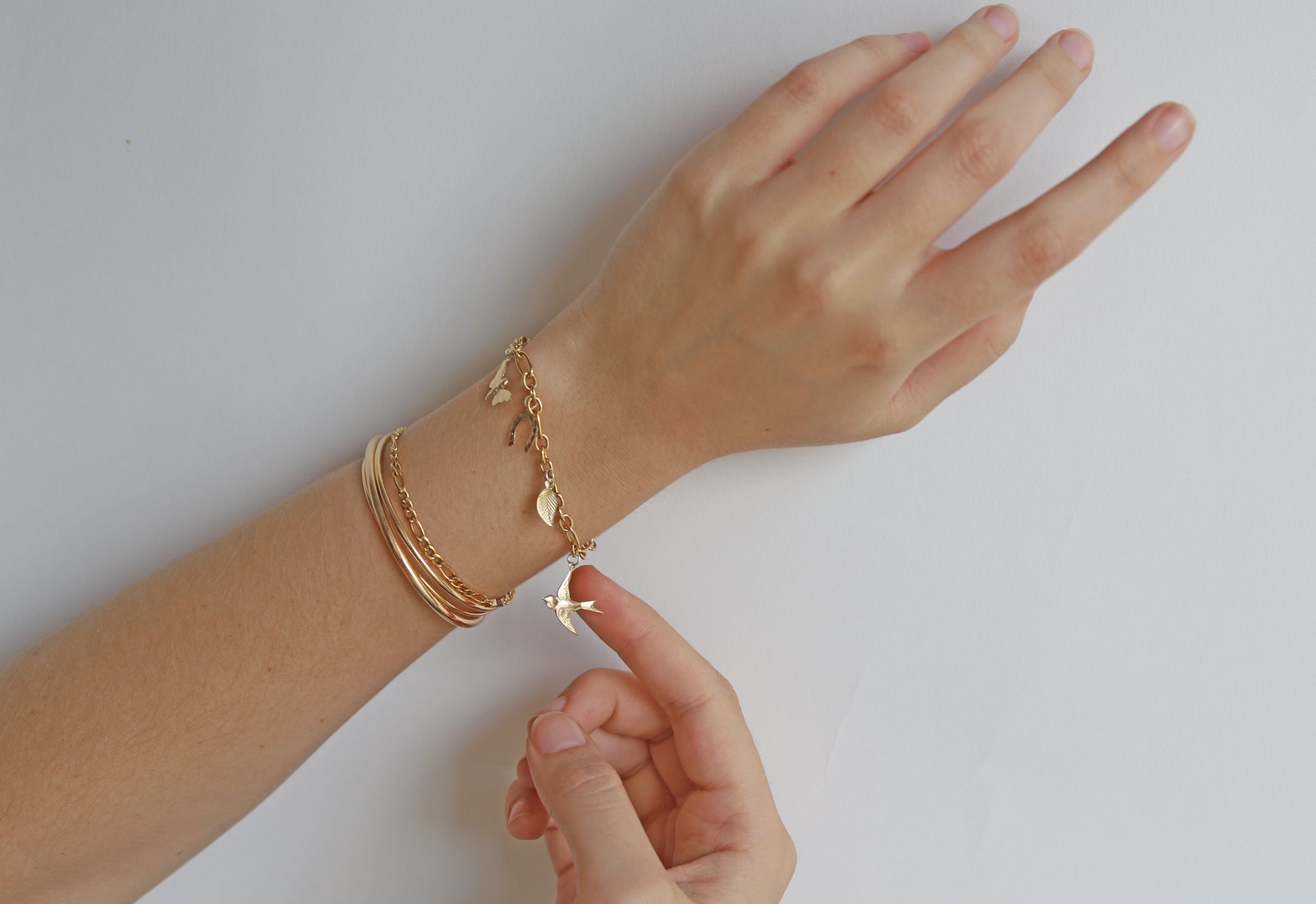 Hand wearing gold bracelets on a white background