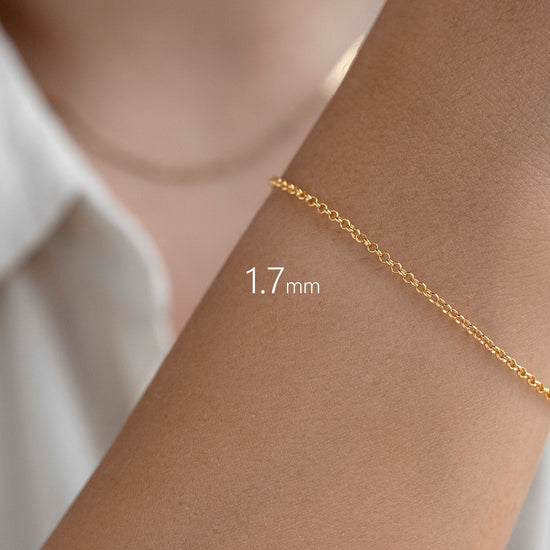 Gold bracelet on a wrist with a measurement label indicating 1.7mm width, against a neutral background.