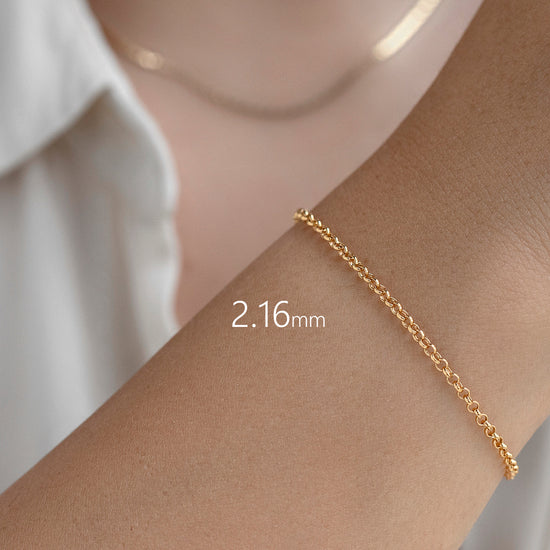 Gold bracelet on a wrist with a white shirt background