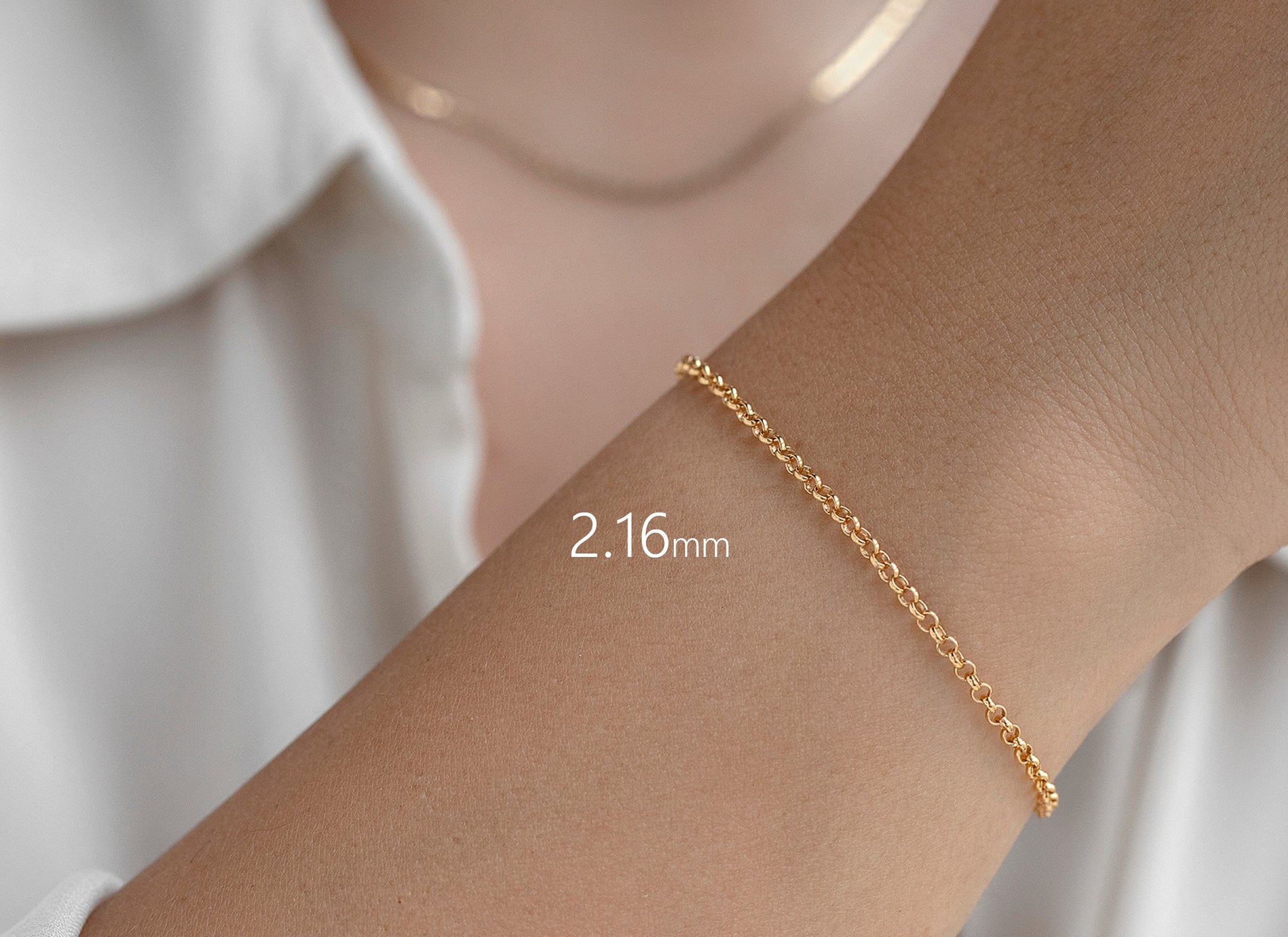 Gold bracelet on a wrist with a white shirt background