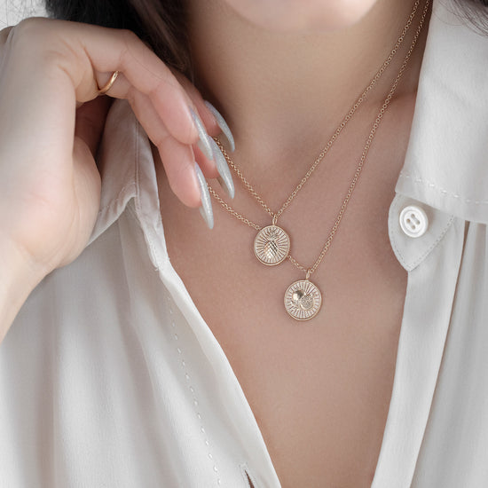 Necklace with circular pendants worn by a person in a white shirt.