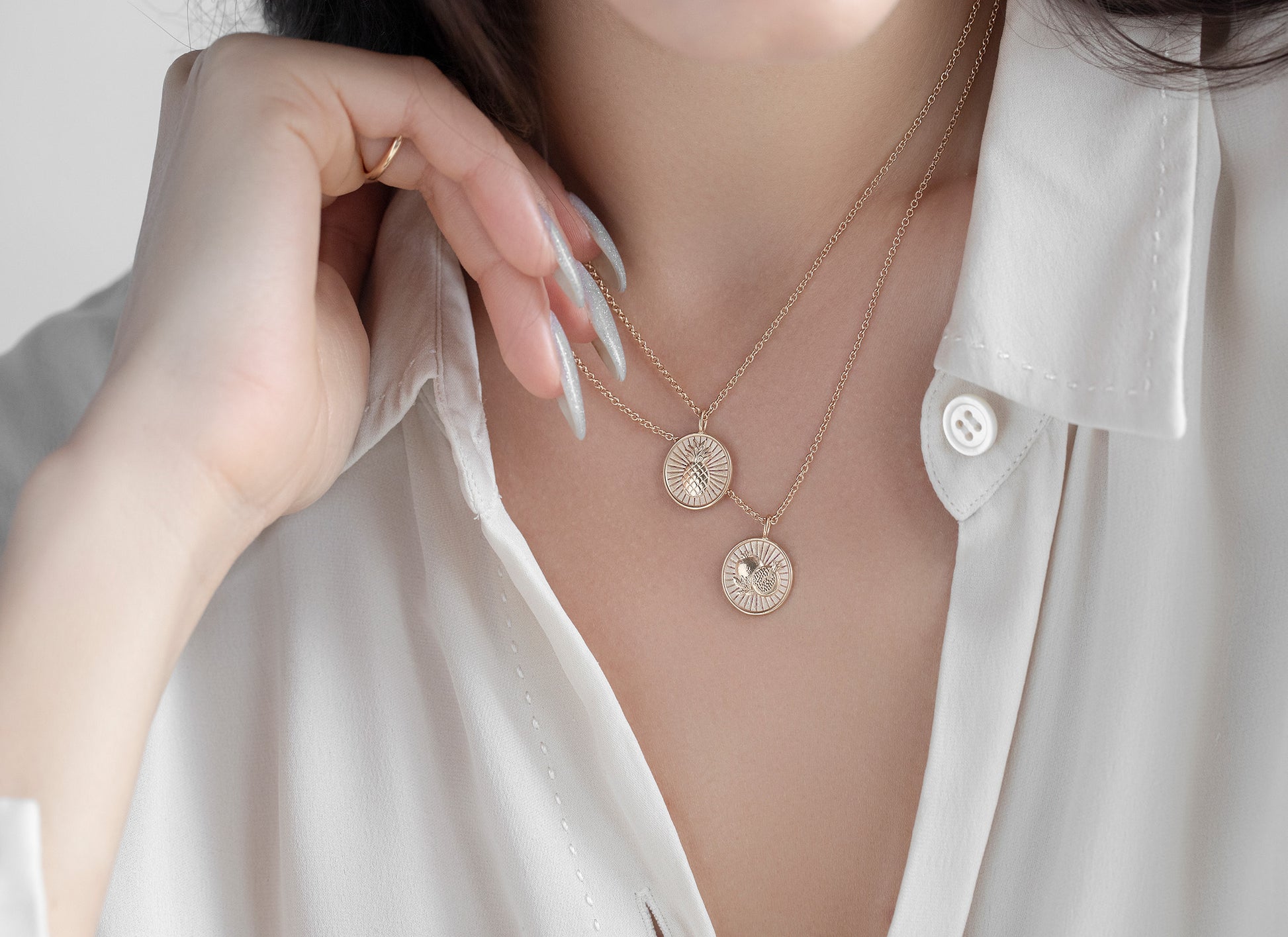 Necklace with circular pendants worn by a person in a white shirt.
