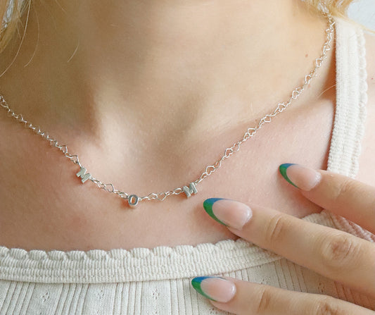 Silver necklace being worn on a person's neck with a close-up of the necklace.