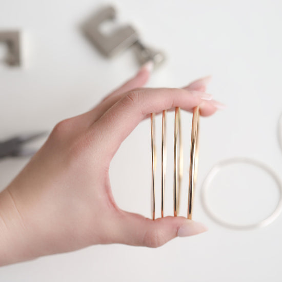 Hand holding gold permanent bangles with blurred background