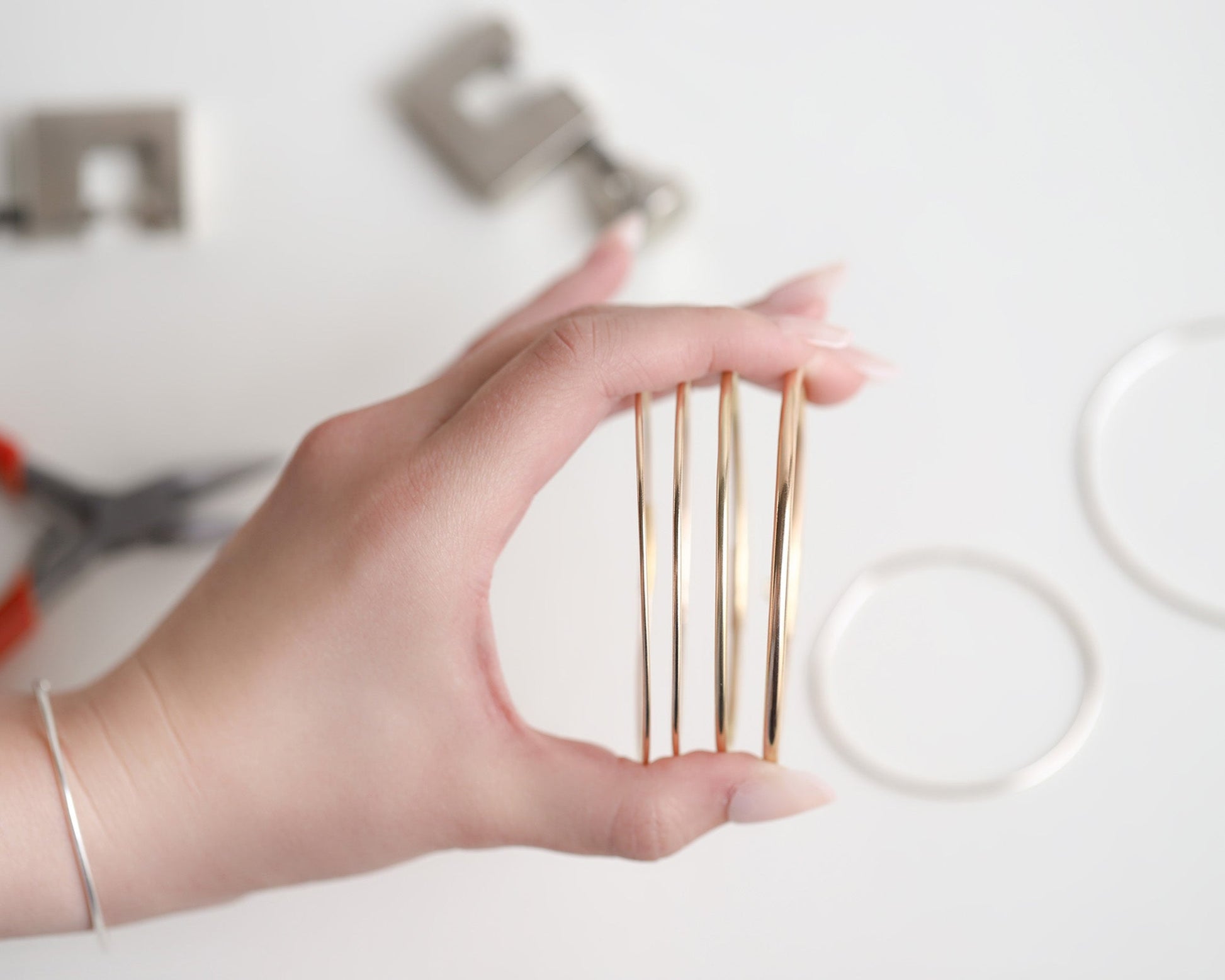 Hand holding wired gold bangles with blurred background