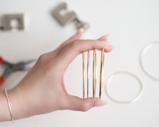 Hand holding wired gold bangles with blurred background