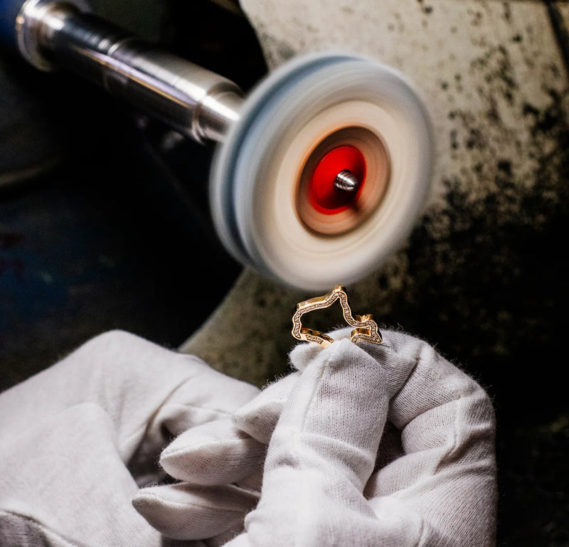 Gold invisible clasp being worked on by a jeweler using a polishing machine.