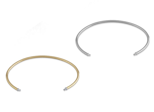 Two round wire permanent cuffs, one in gold color and the other in silver color, both with bails on the caps for attaching charms.