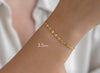 Gold bracelet on a wrist with a plain background