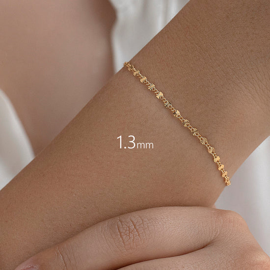 Gold starburst bracelet on a wrist with a measurement label '1.3 mm' against a white background